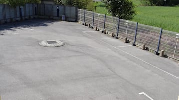 Pysäköintialue, jossa on merkityt pysäköintiruudut, ja viemärin kansi.