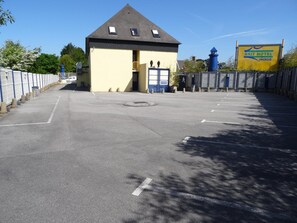 A parking lot with a building that has a yellow facade and a blue door, labeled "BRIT HOTEL ROISE". - Brit Hotel Iroise (Plougastel-Daoulas)