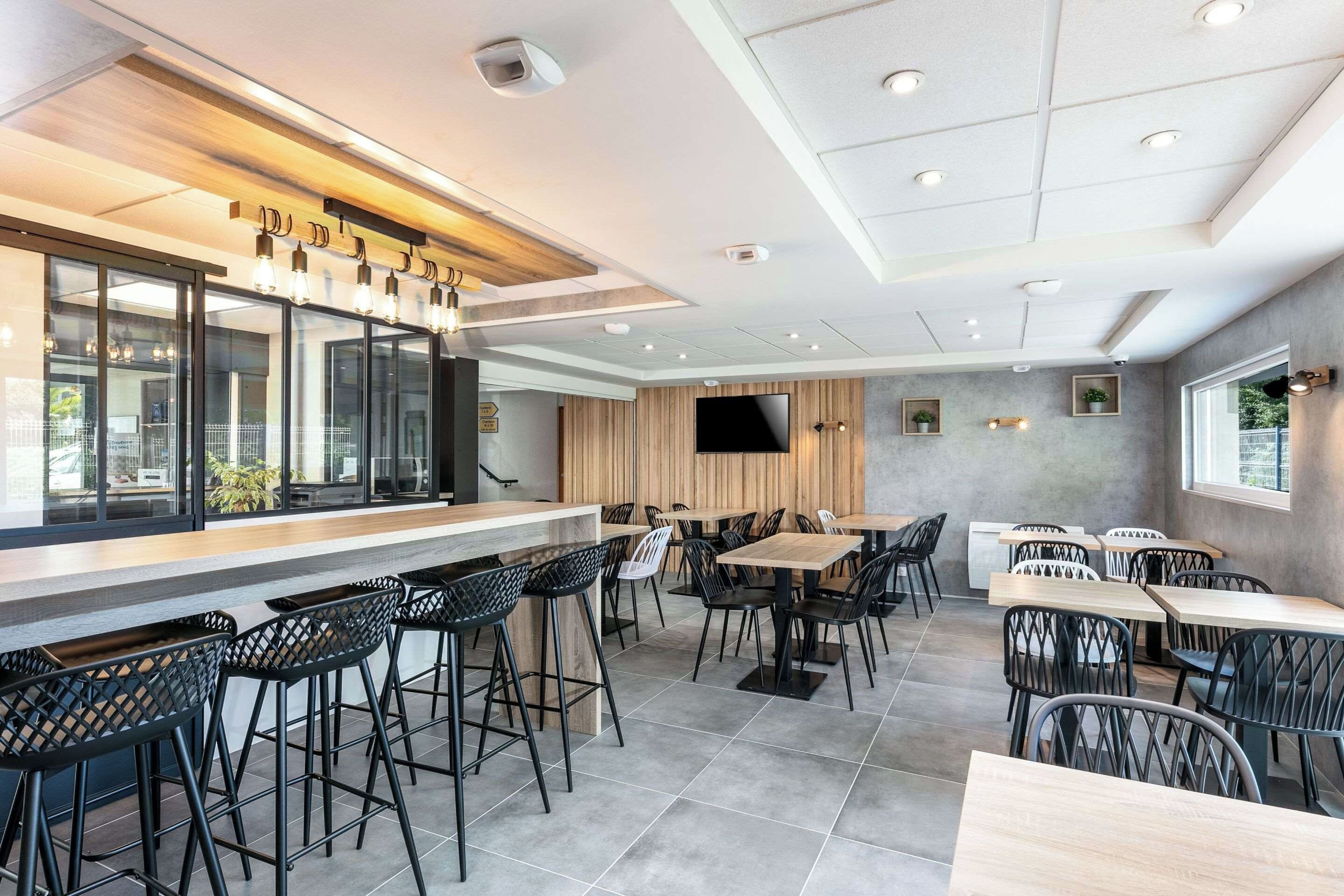 Een modern restaurantinterieur met een bar, zitplaatsen en een flatscreen-tv.