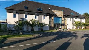 Un hotel de fachada de piedra, con varias ventanas y un estacionamiento.