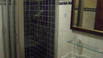 A bathroom with a glass shower enclosure, a white sink, and a mirror.