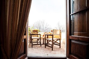 An open wooden door leading to an outdoor patio with a table and chairs. - Palazzo al Torrione 2 (San Gimignano)