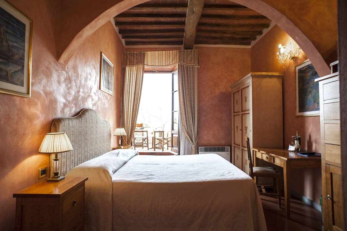 A bedroom with a bed, a desk, a chair, and a lamp.