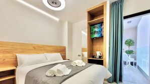 A modern hotel room with a wooden headboard, a large bed with white linens, a bedside table with a coffee maker, and a view of the balcony. - Puerto Azul (Puerto de la Cruz)