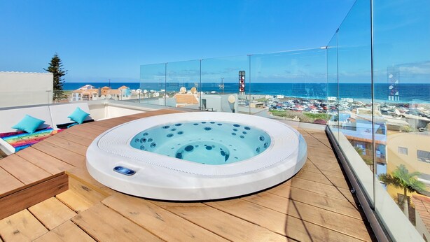 A hot tub on a wooden deck with a view of the sea and buildings. - Puerto Azul (Puerto de la Cruz)