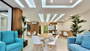 A modern hotel lobby with a central wooden table, white chairs, and blue sofas. - Puerto Azul (Puerto de la Cruz)