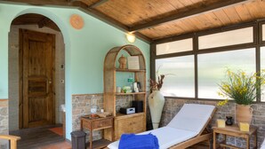 Ein Zimmer mit einem hölzernen Bett, einer Steinsäule, einem Korbschrank und einem Fenster mit gelben Blumen.