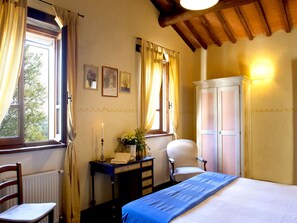 Une chambre à coucher comprenant un lit, un bureau, une chaise, une armoire et une fenêtre avec des rideaux.