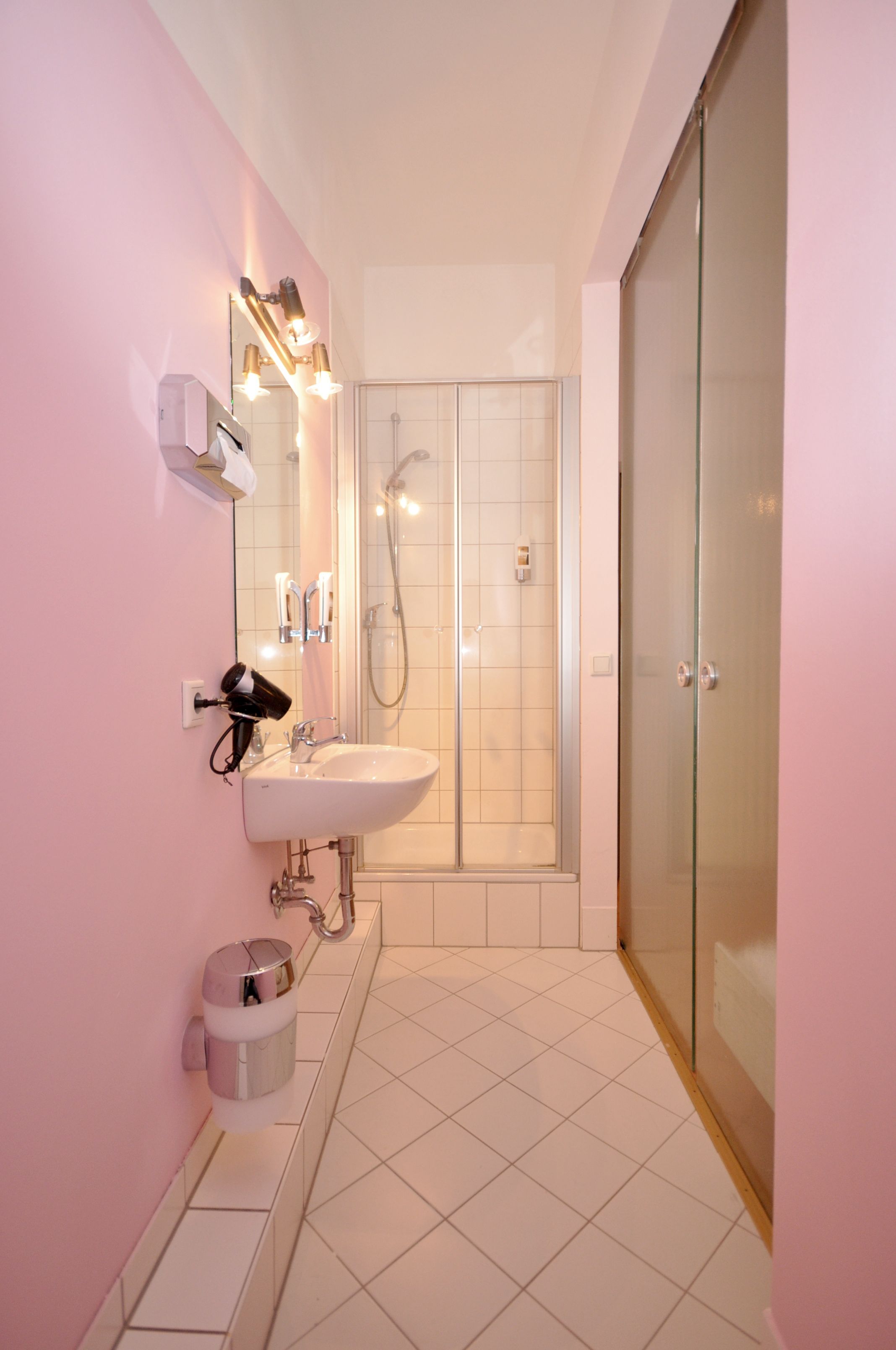 Un baño moderno con cabina de ducha de vidrio, un lavabo blanco y un espejo de tocador.