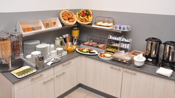 A breakfast buffet with various food items, including bread, fruits, and dairy products. - Apadana Hotel (FRANKFURT AM MAIN)