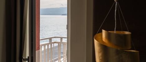 A view from a room with a window overlooking a body of water and a balcony.