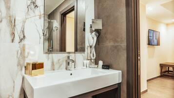 Un baño con lavamanos de mármol, secador de pelo, espejo y toallero.