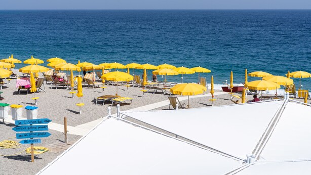 A beach with yellow umbrellas and white lounge chairs. - Hotel Palace (Catanzaro)