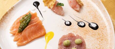A white plate with various food items including salmon, asparagus, and a tartare.