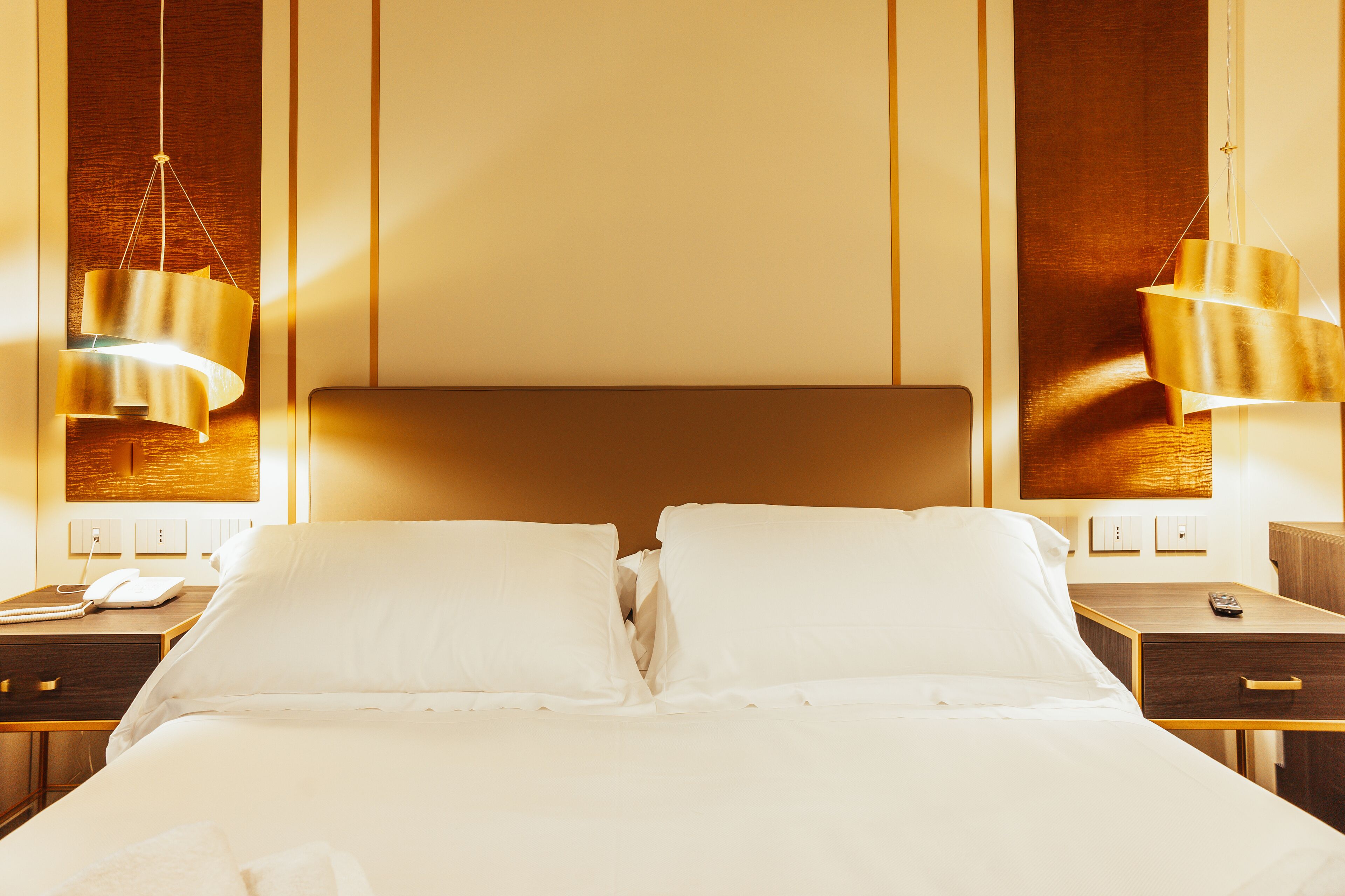 Une chambre d’hôtel avec un grand lit, des tables de chevet, une petite table et une lampe suspendue.