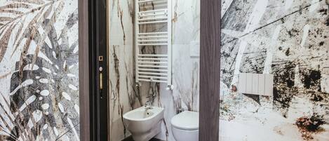 A bathroom with a bidet, toilet, and a towel rack.