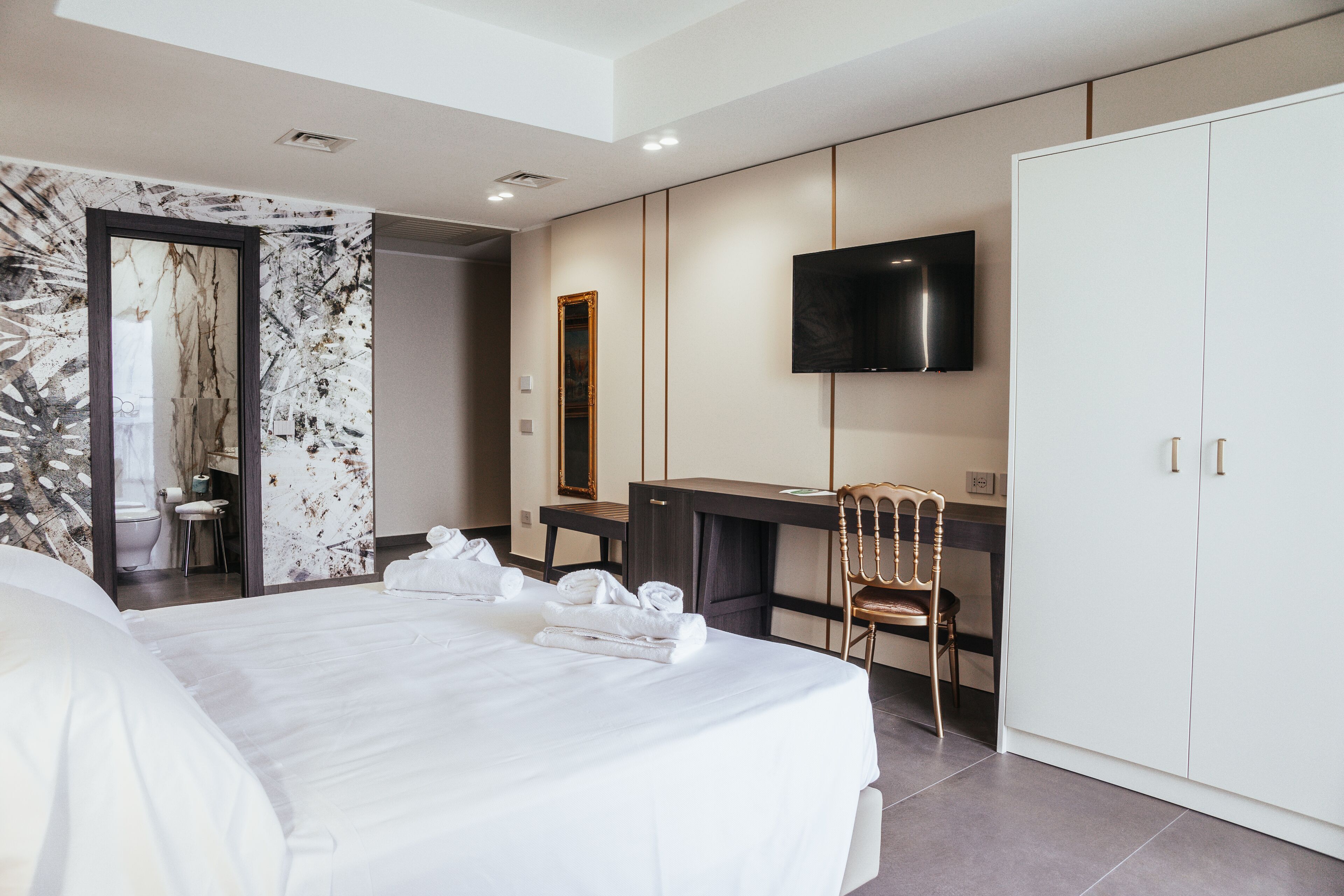 Una habitación de hotel moderna con una cama grande, un escritorio, un televisor y un armario.