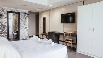 Ein modernes Hotelzimmer mit einem großen Bett, einem Schreibtisch, einem Fernseher und einem Kleiderschrank.