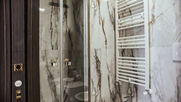 A bathroom with a glass-enclosed shower, a white sink, and a marble wall.