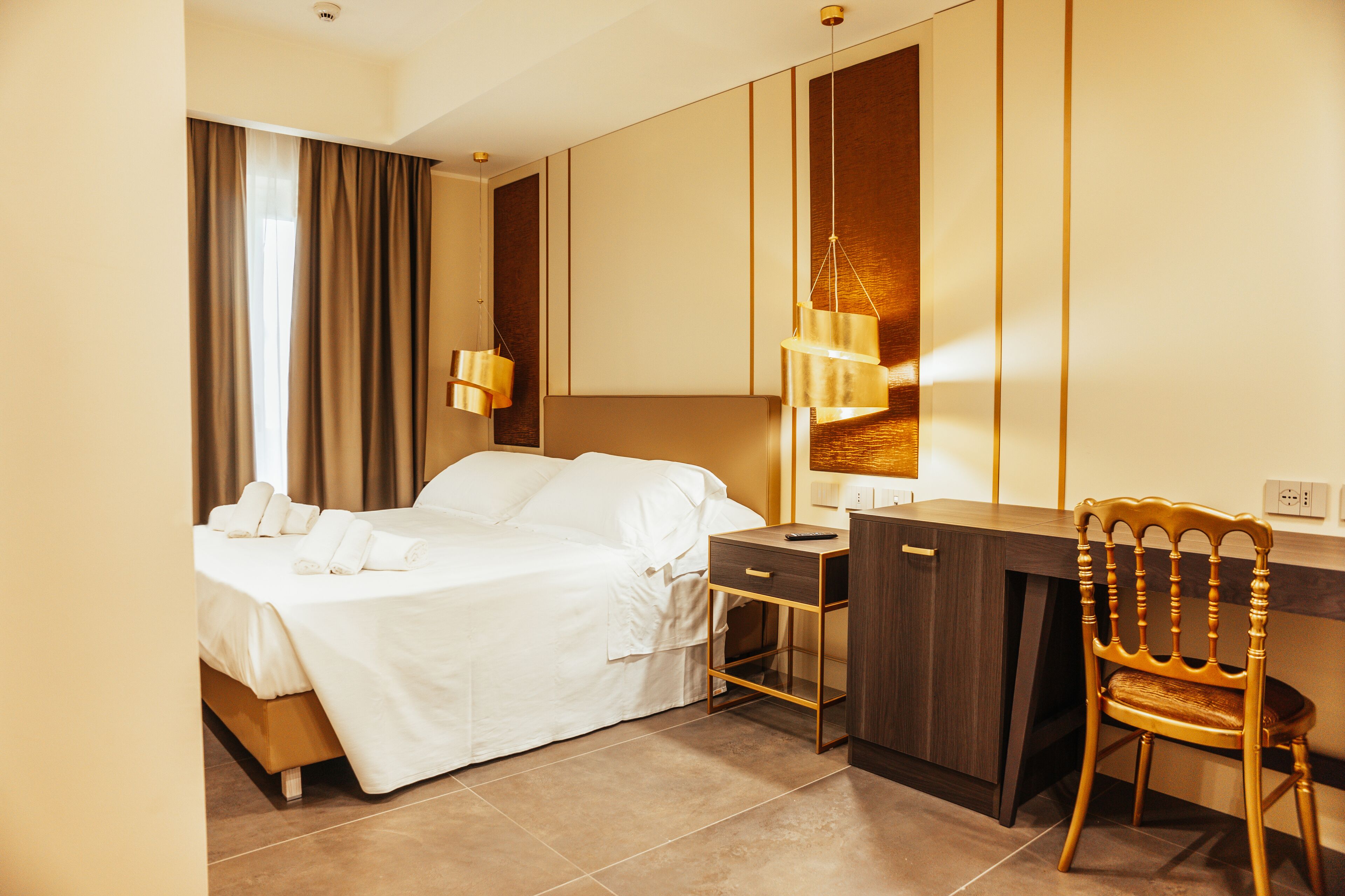 Una habitación de hotel con una cama, un escritorio, una silla y una lámpara.