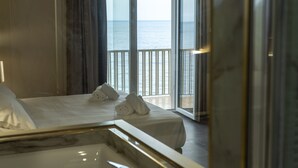 A hotel room with a bed, a bathroom with a marble sink, and a balcony with a view of the sea. - Hotel Palace (Catanzaro)