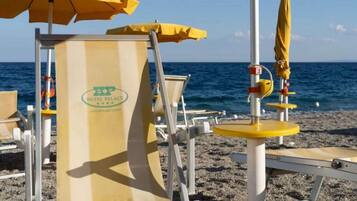 Una sedia da spiaggia con un ombrellone giallo, un canotto di salvataggio e un cartello per Hotel Palace Catanzaro Lido.