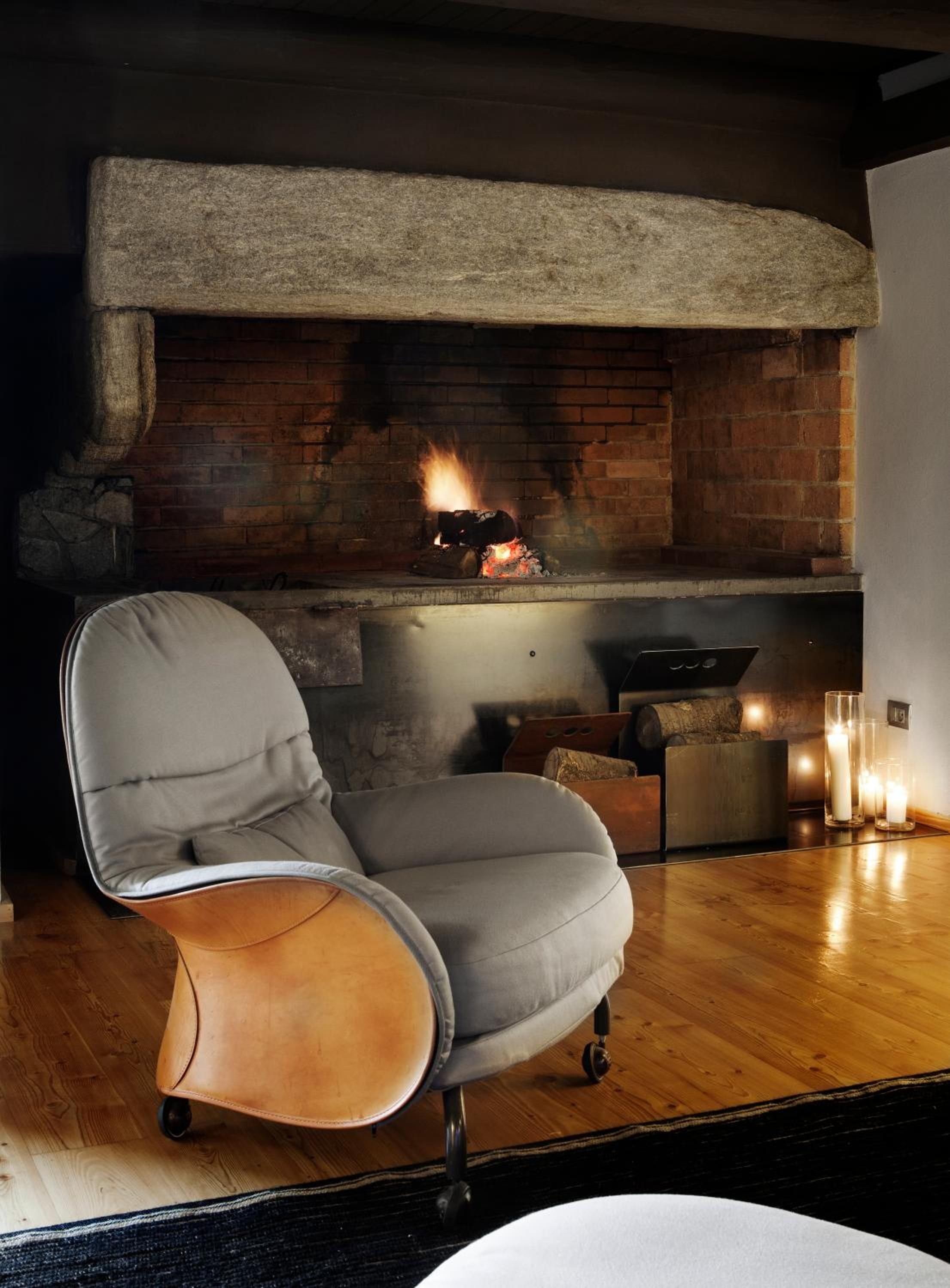 A modern living room with a stone fireplace, a leather armchair, and a wooden floor.