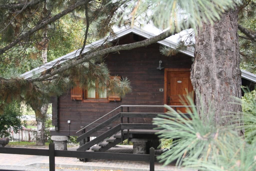 A rustic wooden cabin with a wooden staircase leading to the entrance.