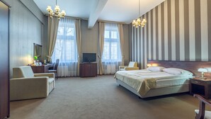 A hotel room with a large bed, a desk with a computer, a chair, and a TV. - Hotel Royal (Kraków)