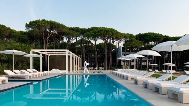 A swimming pool with lounge chairs and umbrellas, surrounded by trees. - Hotel Mediterraneo (Jesolo)