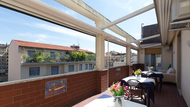 Una terraza en la azotea con una mesa, sillas, un mural y vistas a edificios.