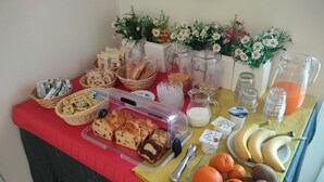 Un bufé de desayuno con diversas opciones de comida, como pan, bollería, frutas y productos lácteos.