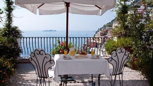 A table set for breakfast with a view of the sea and buildings in the background. - Villa Rosa (Positano)