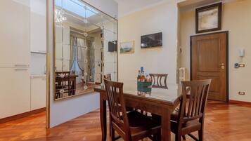 Un coin repas avec une table en bois, des chaises, un grand miroir et une porte en bois.