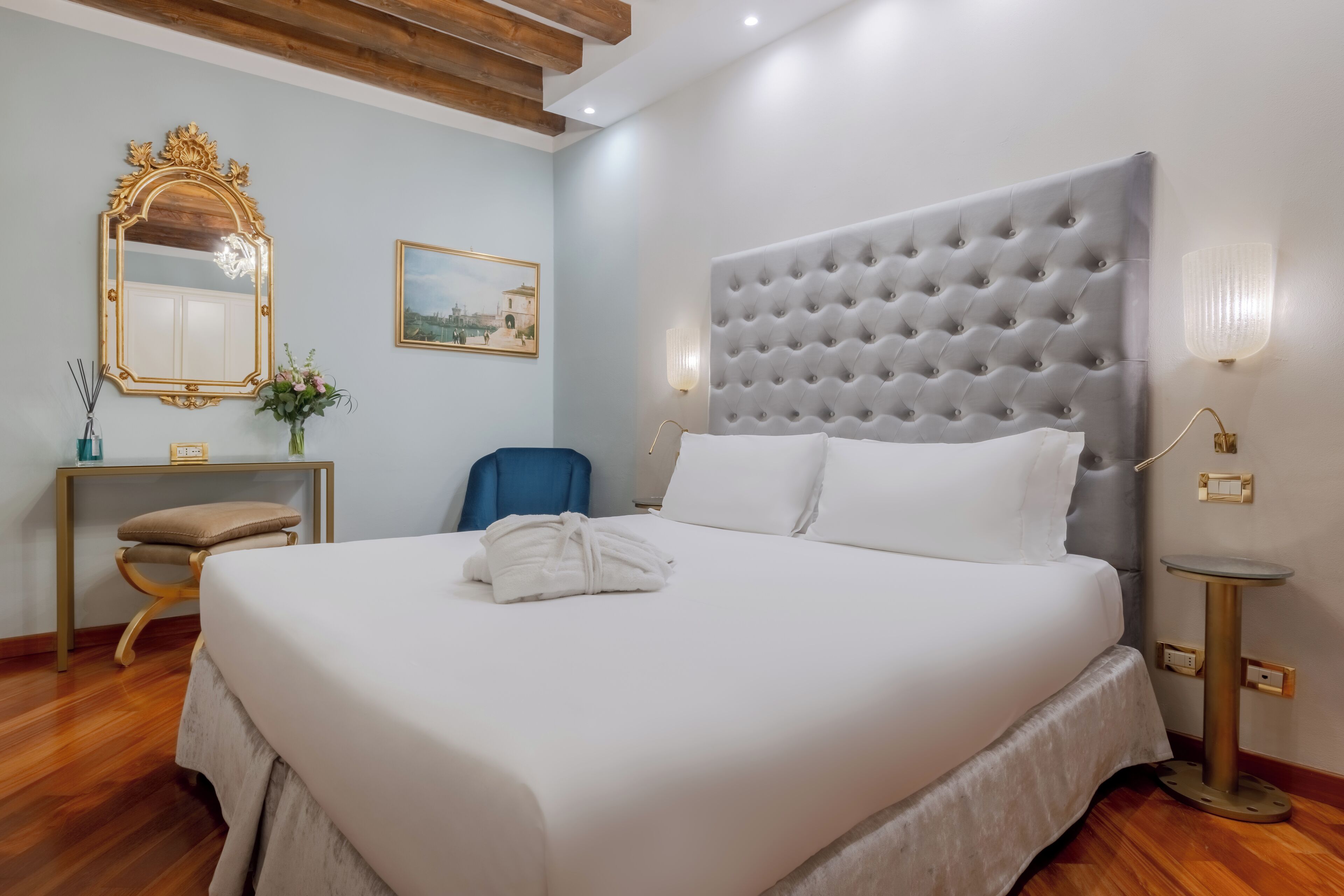 A neatly made bed with white linens, a tufted headboard, and a bedside table with a lamp.