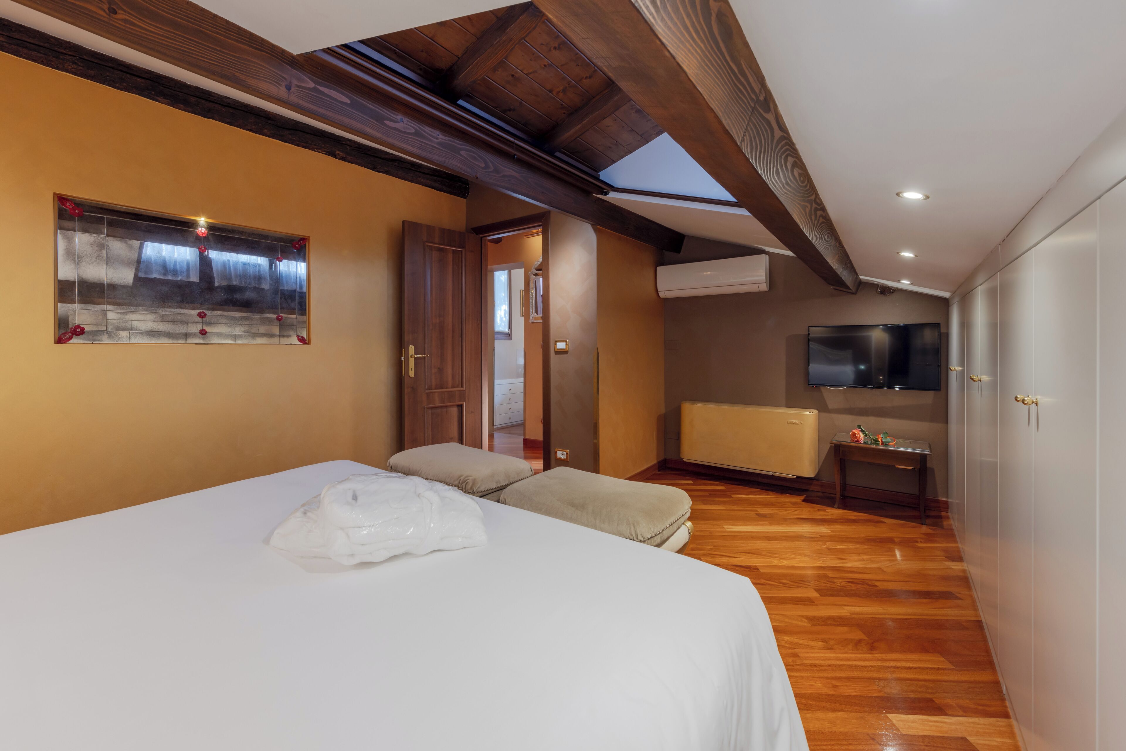 Un dormitorio con cama, un banco, un televisor y un armario.