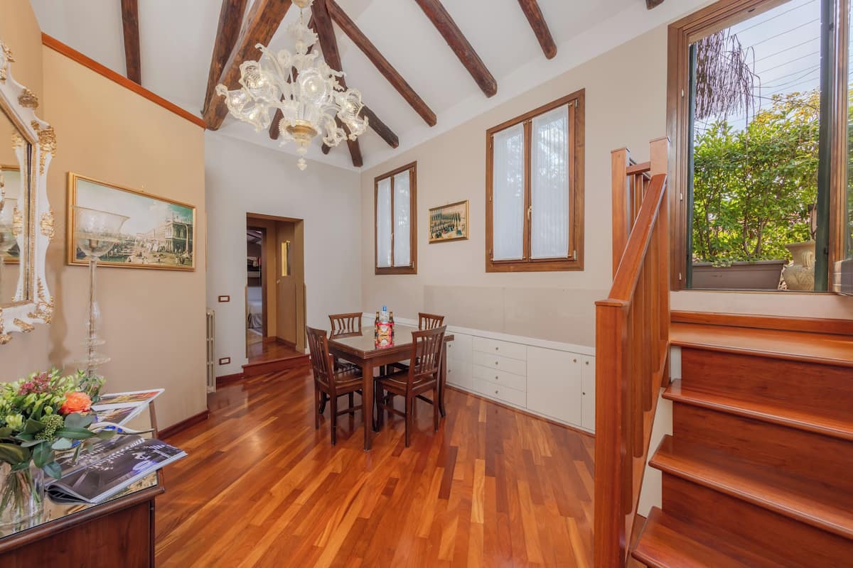 A dining area with wooden flooring, a chandelier, and a staircase.