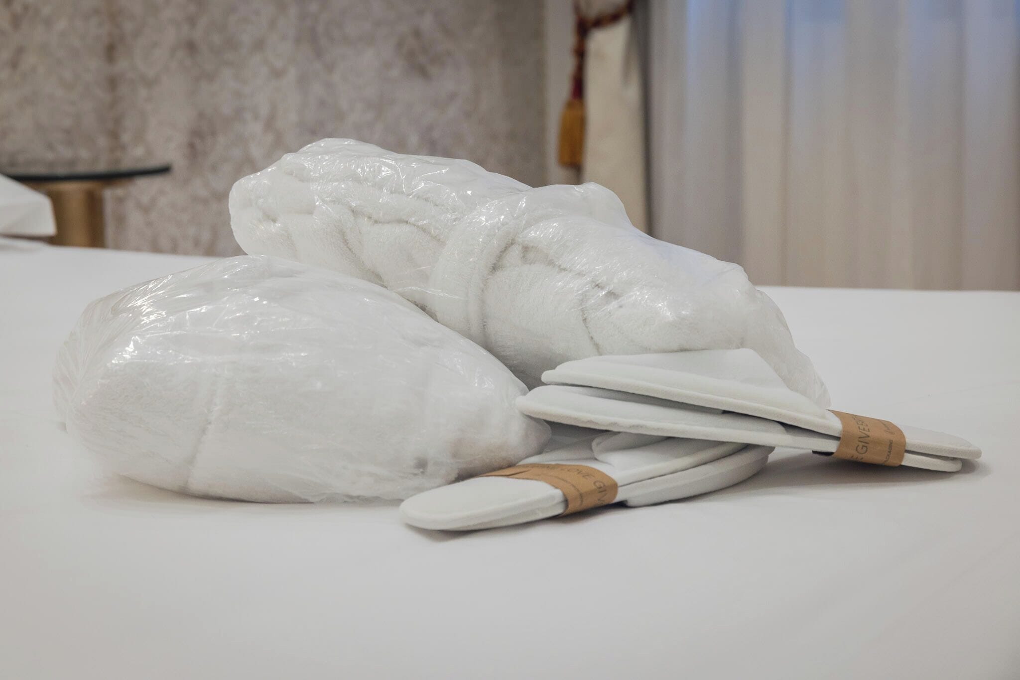 A bed with white bedding and a rolled-up blanket.