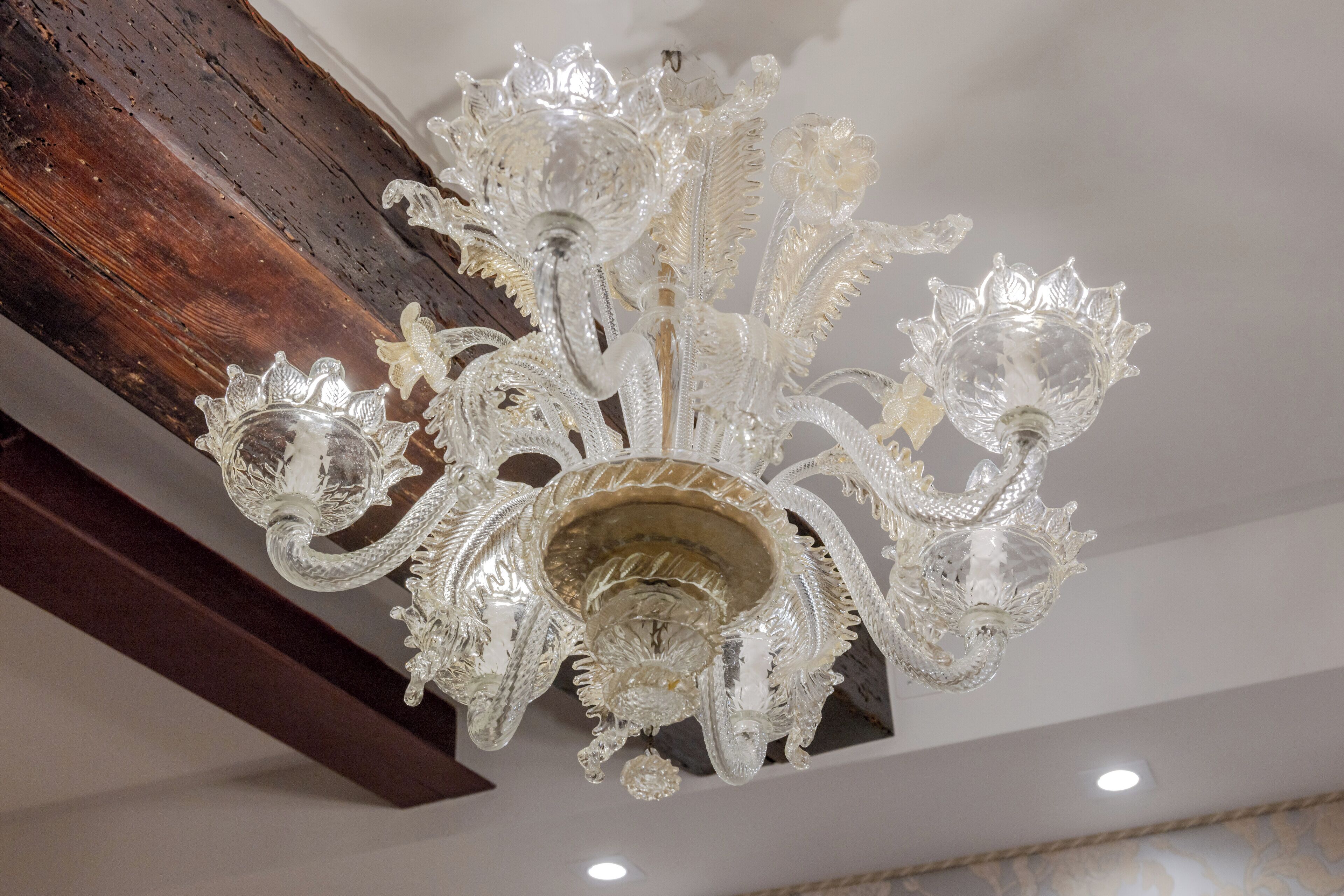 A chandelier with intricate crystal details hanging from a wooden beam.