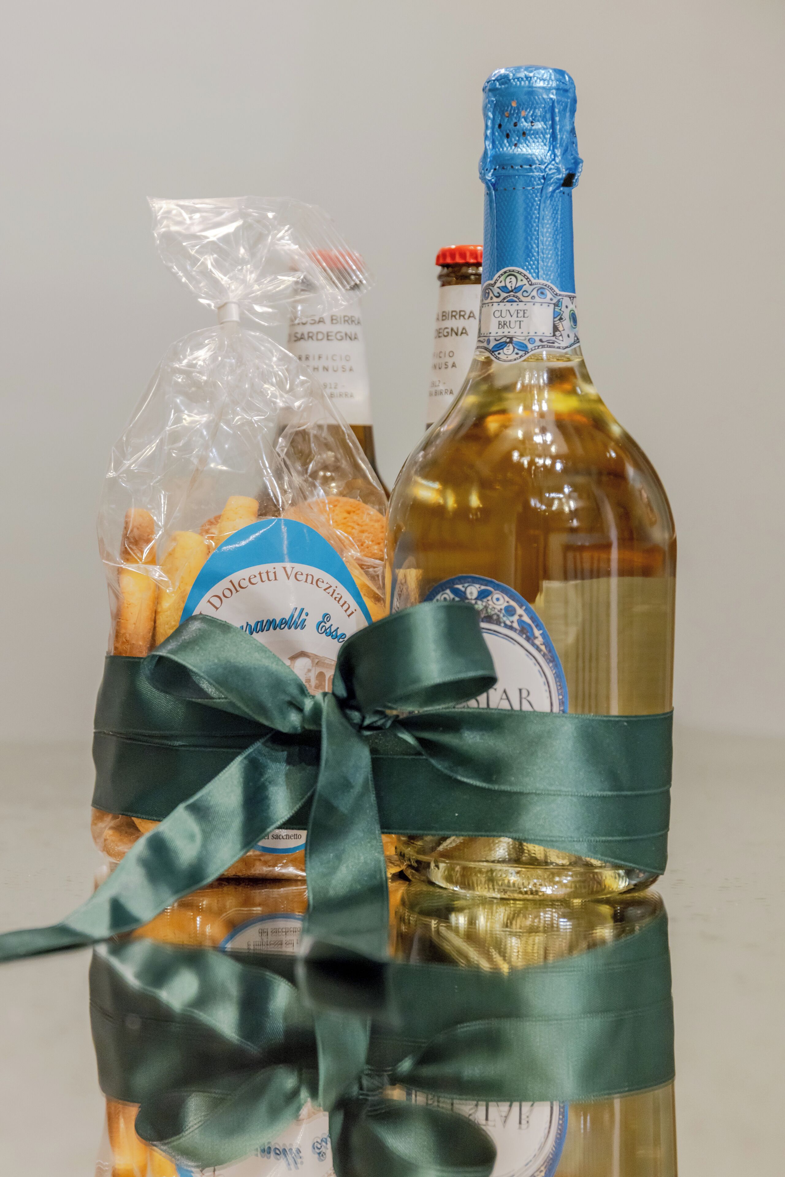 Eine Flasche Cuvée Brut Wein und eine Geschenktüte mit Dolcetti Veneziani Snacks.