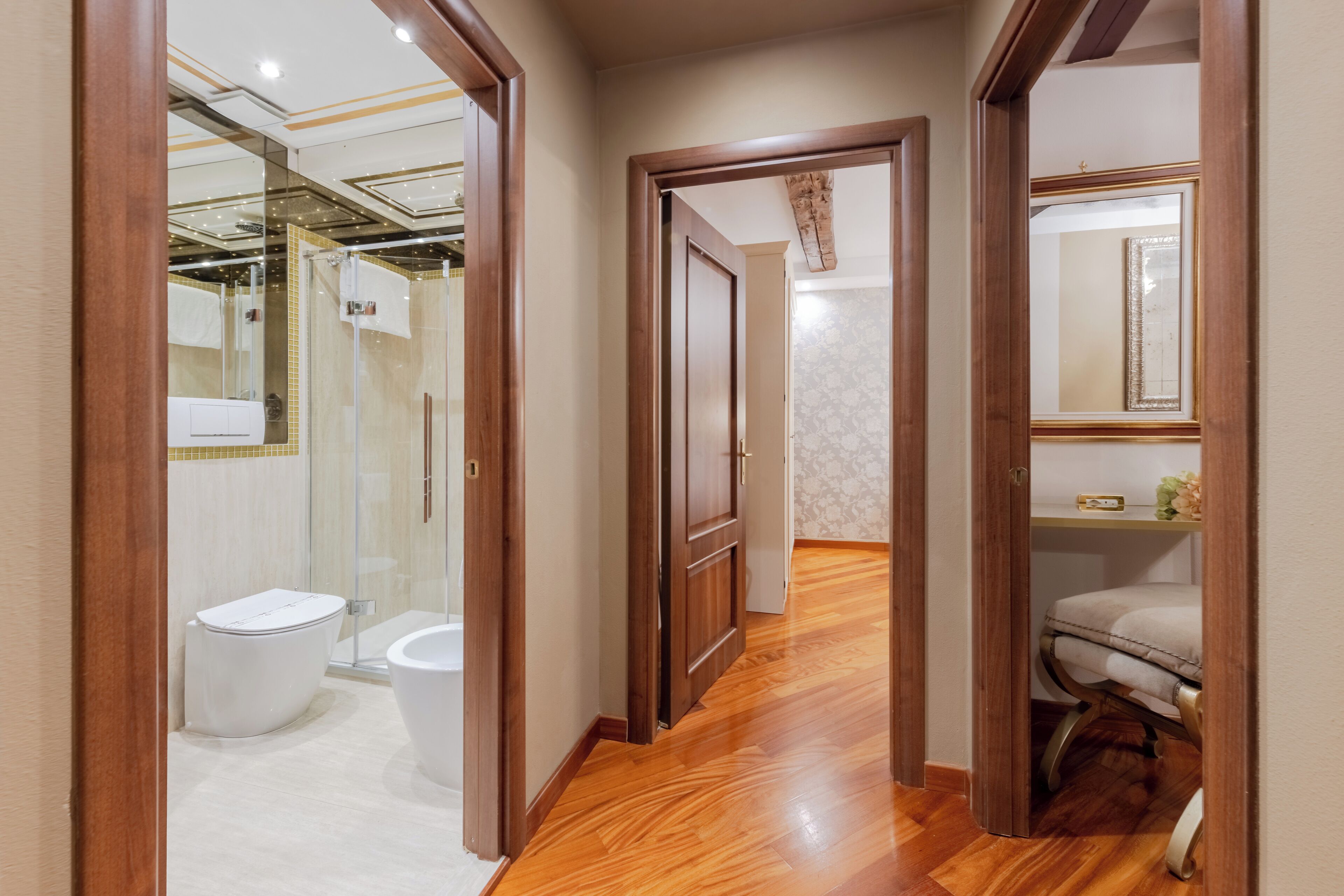 A hallway leading to a bathroom with a toilet, bidet, and shower.