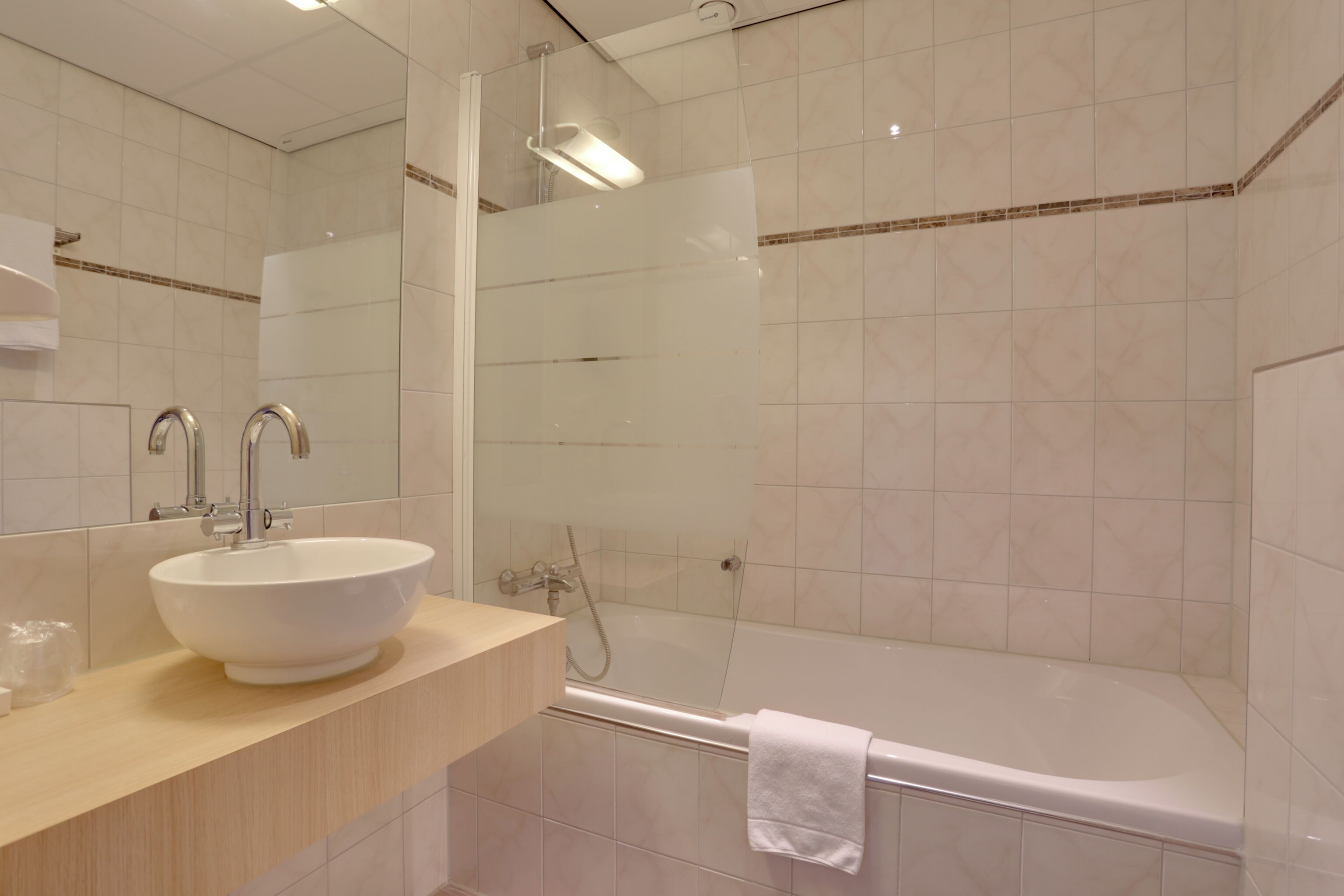 A modern bathroom with a large white sink, a glass-enclosed shower, and a bathtub.