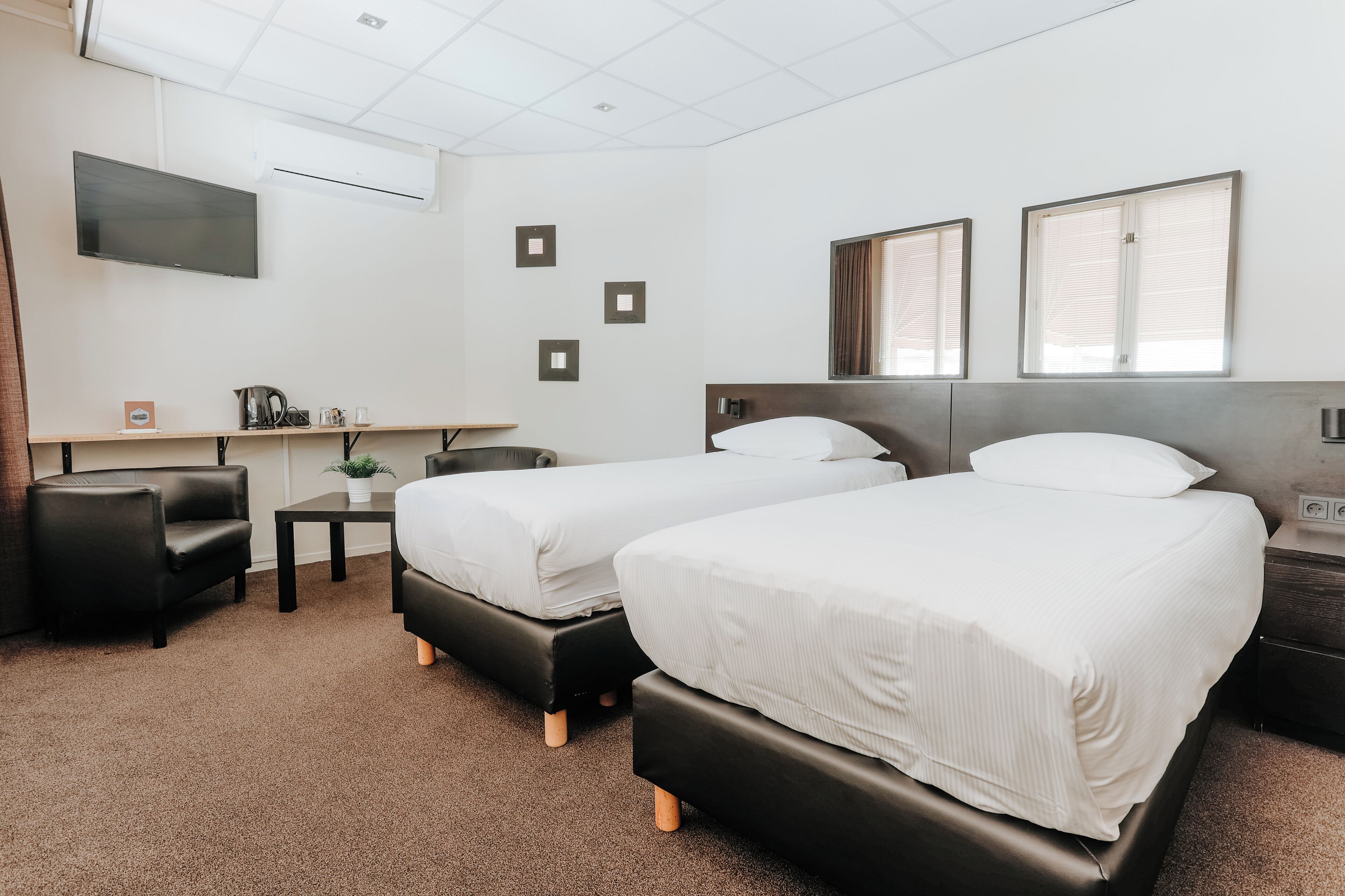 Une chambre d’hôtel avec deux lits, un bureau, une chaise et un téléviseur.