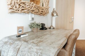 A dining area with a rustic wooden table, a potted plant, a lamp, and a remote control. - Queen Hotel (Eindhoven)
