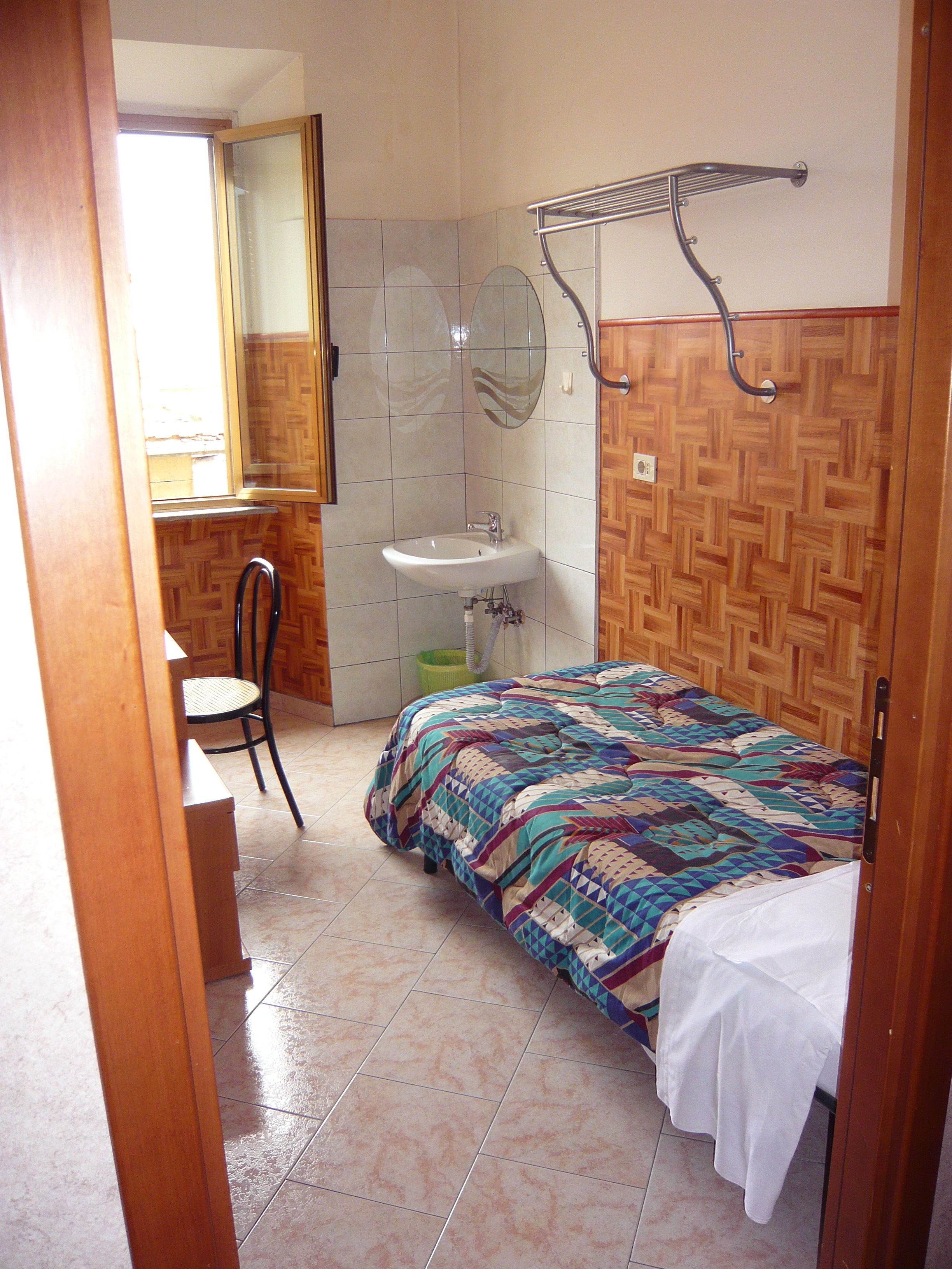 Une chambre à coucher avec un lit, une chaise, un lavabo et un miroir.