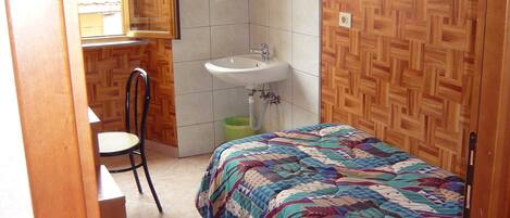 Une chambre à coucher avec un lit, une chaise, un lavabo et un miroir.