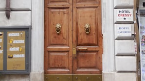 A double wooden door with brass handles, flanked by signs for Hotel Cressy and Hotel Cathrine. - Cressy (Rome)