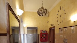 A hotel lobby with a reception desk, a wall clock, a red vending machine, and a tiled floor. - Cressy (Rome)