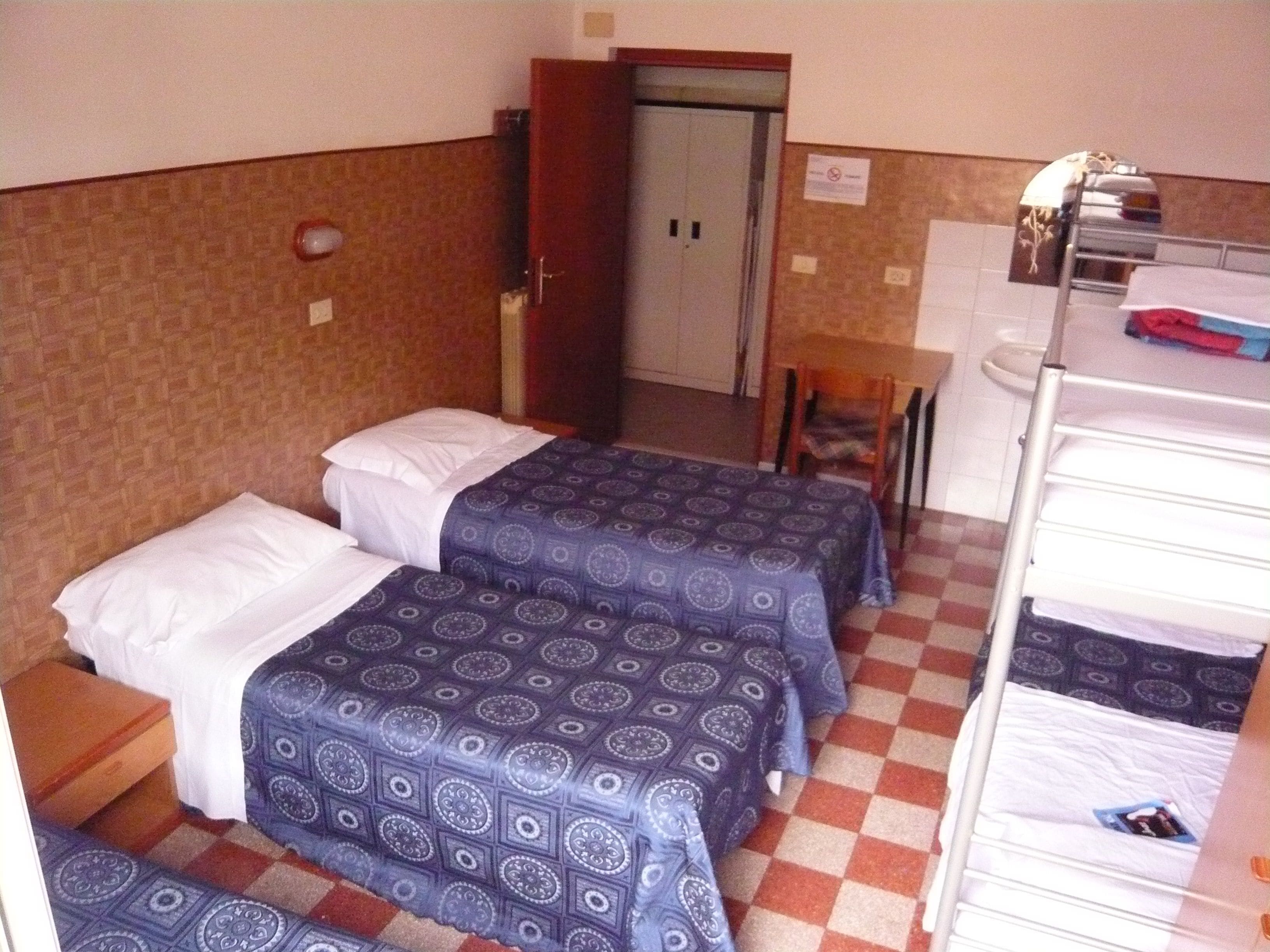 Una habitación de hotel con dos camas, una mesita y una silla.