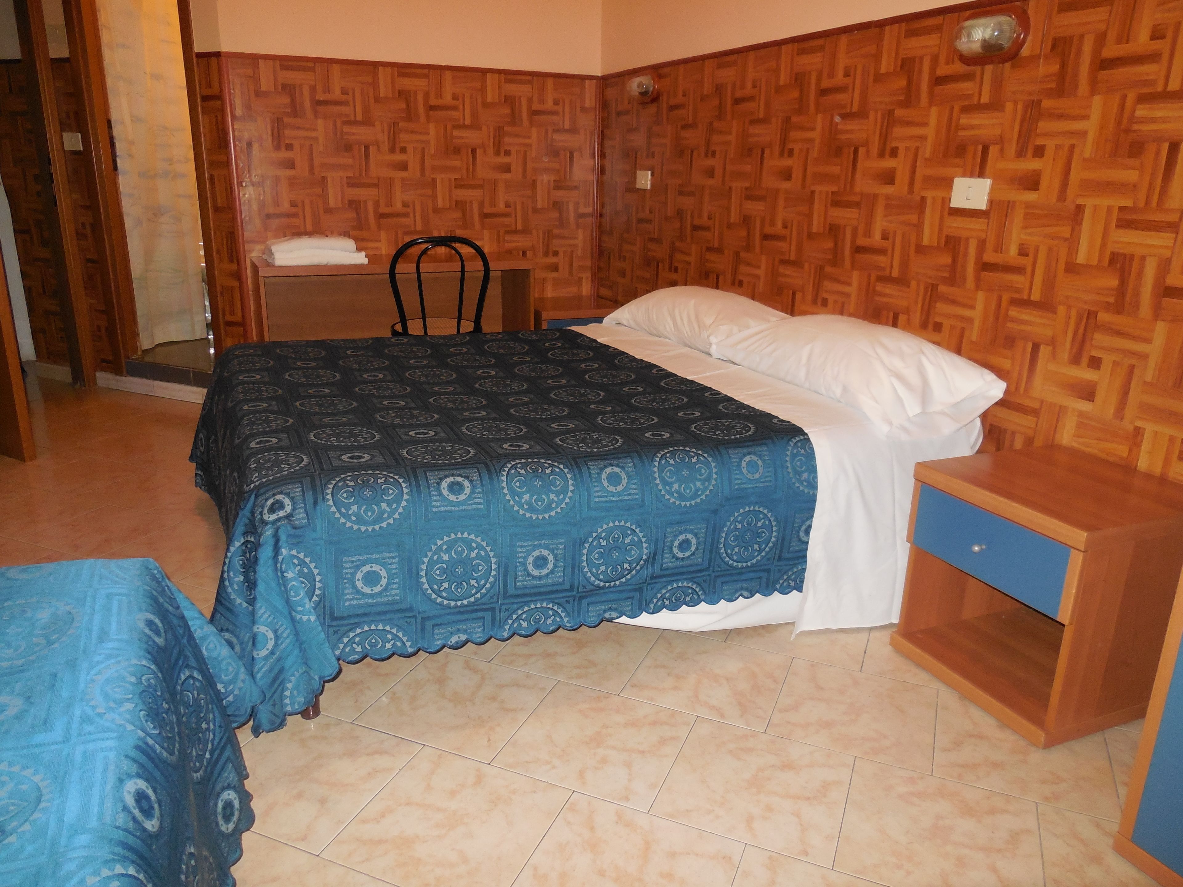 A bedroom with a bed, a nightstand, and a chair.